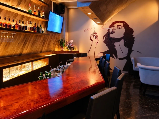 木のカウンターと大きなウォールアートが印象的なBAR Sの店内